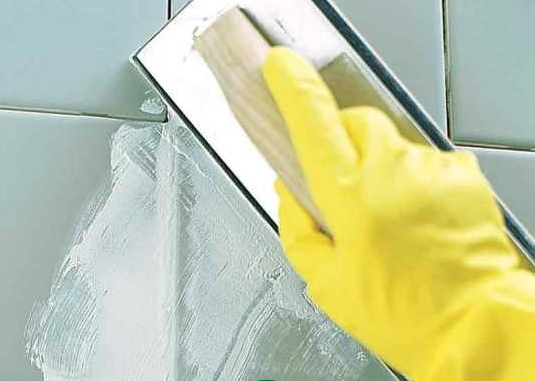 Thợ thi công dùng chổi quét lớp hồ dầu xi măng trắng chống thấm lên tường